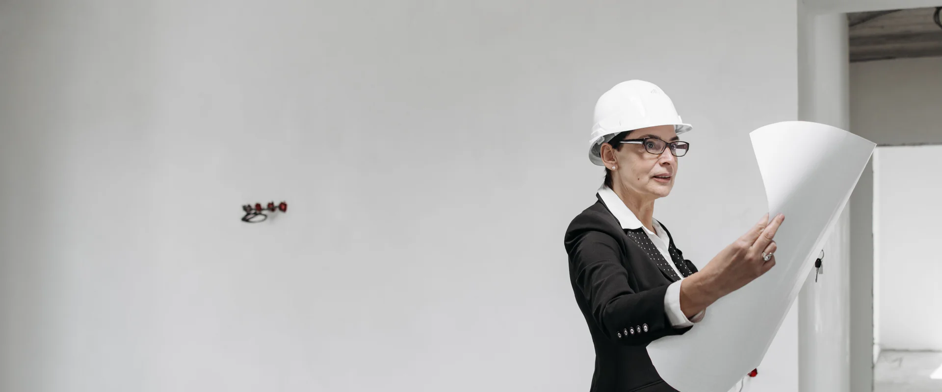 Architektin mit Bauhelm prüft einen Plan in einem hellen Rohbau