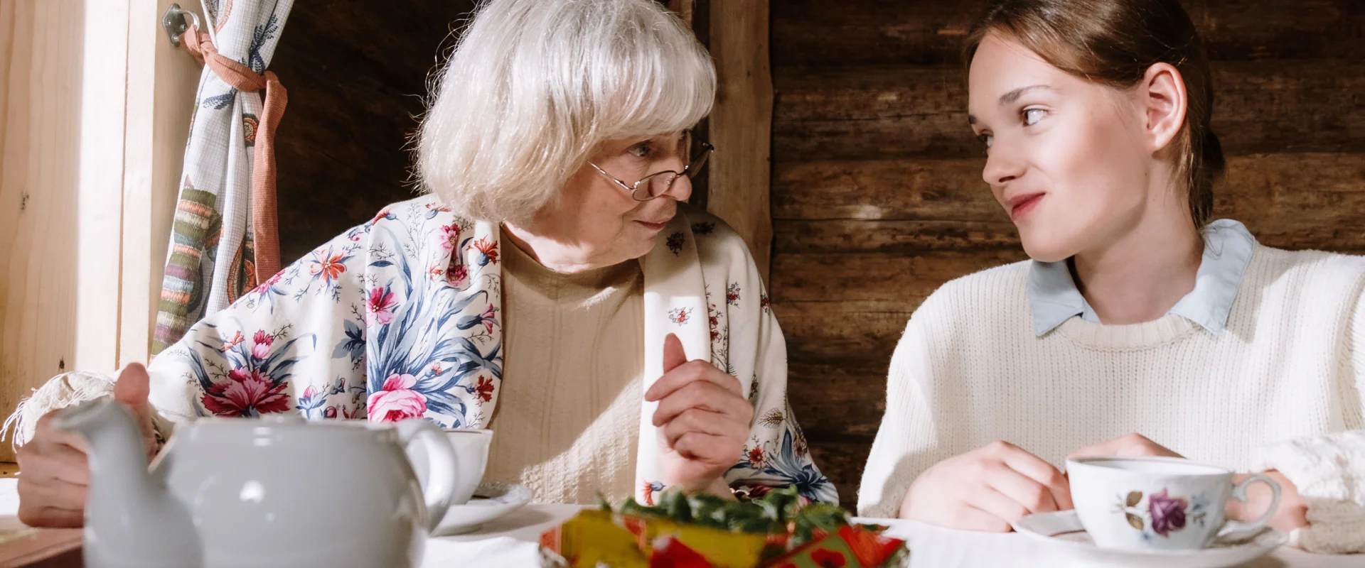 Großmutter und erwachsene Enkelin im Gespräch beim Tee