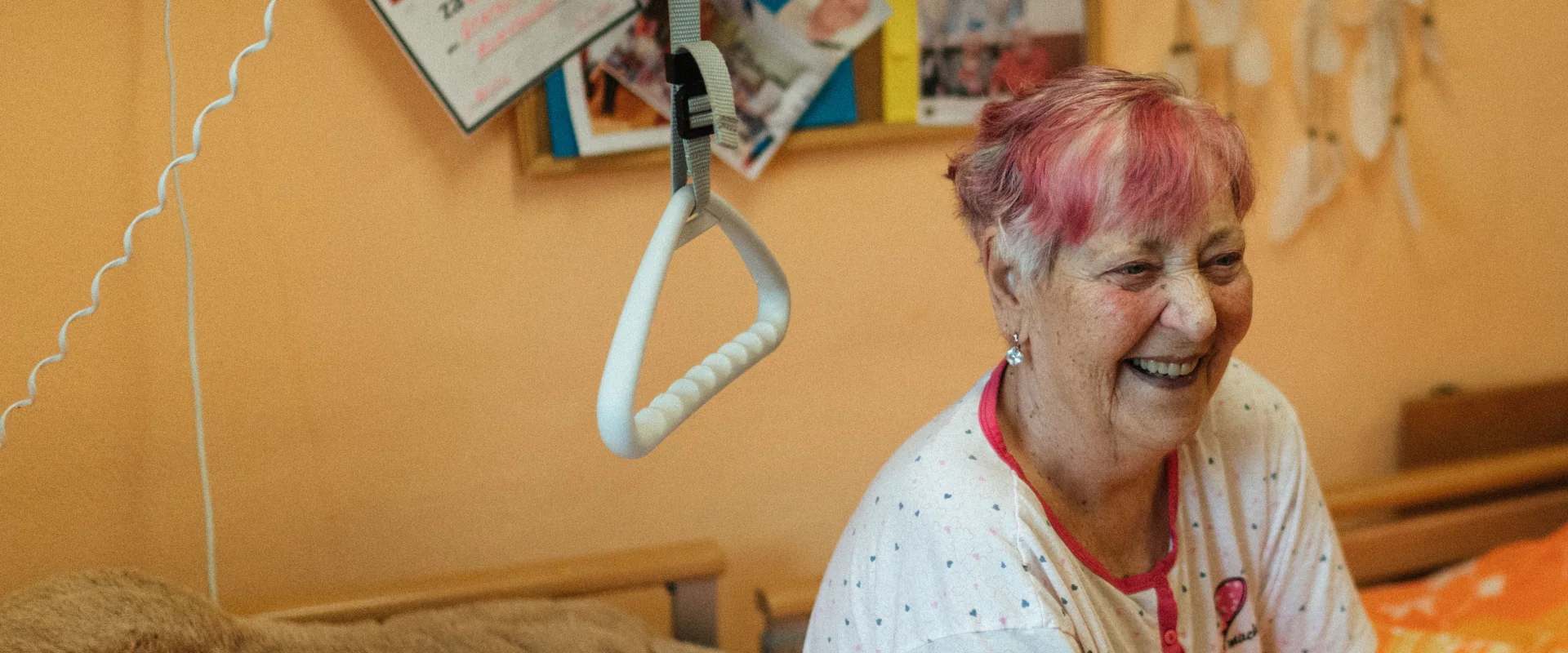 Lachende Patientin sitzt in ihrem hellen Krankenzimmer auf dem Bett
