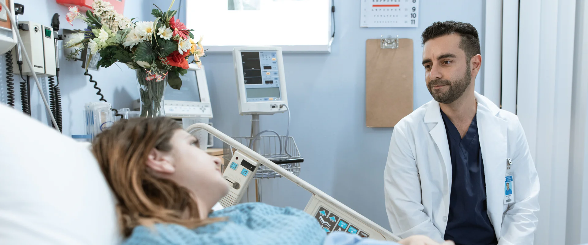 Arzt spricht am Bett mit einer Patientin im hellen Einzelzimmer