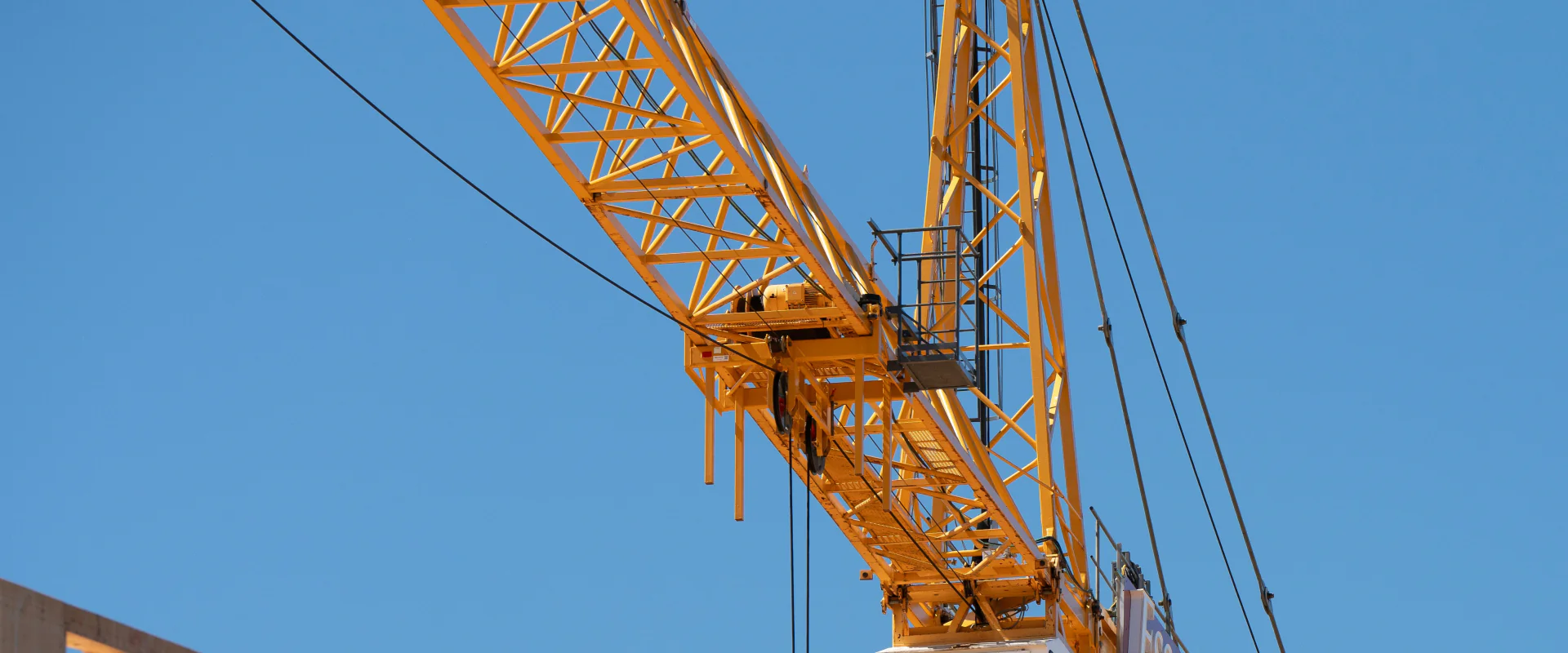 Turmkran über einem Neubau in Holzrahmenbauweise vor blauem Himmel