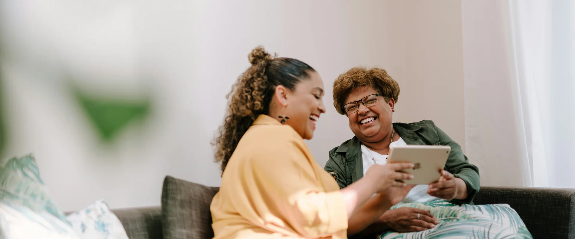 Zwei Frauen lachen gemeinsam auf dem Sofa