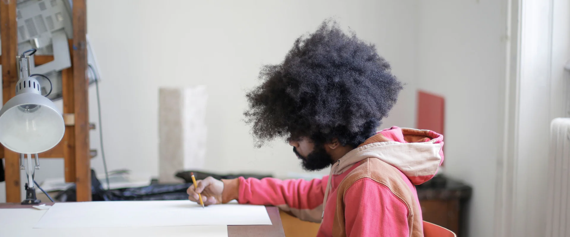 Designer zeichnet am Zeichentisch in seinem hellen Atelier