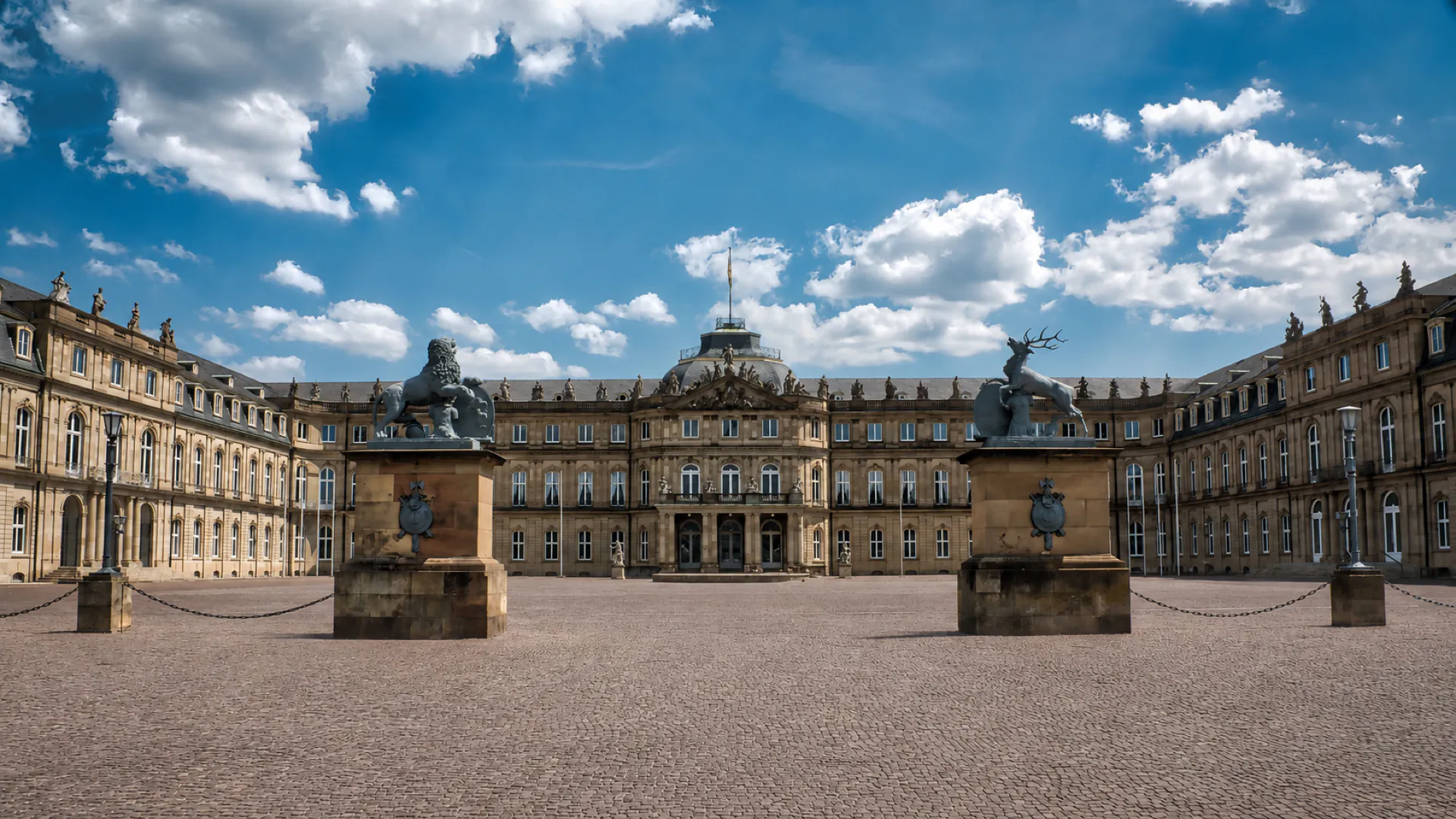 Das Neue Schloss am Stuttgarter Schlossplatz bei Tageslicht, flankiert von den Standbildern mit Löwe und Hirsch