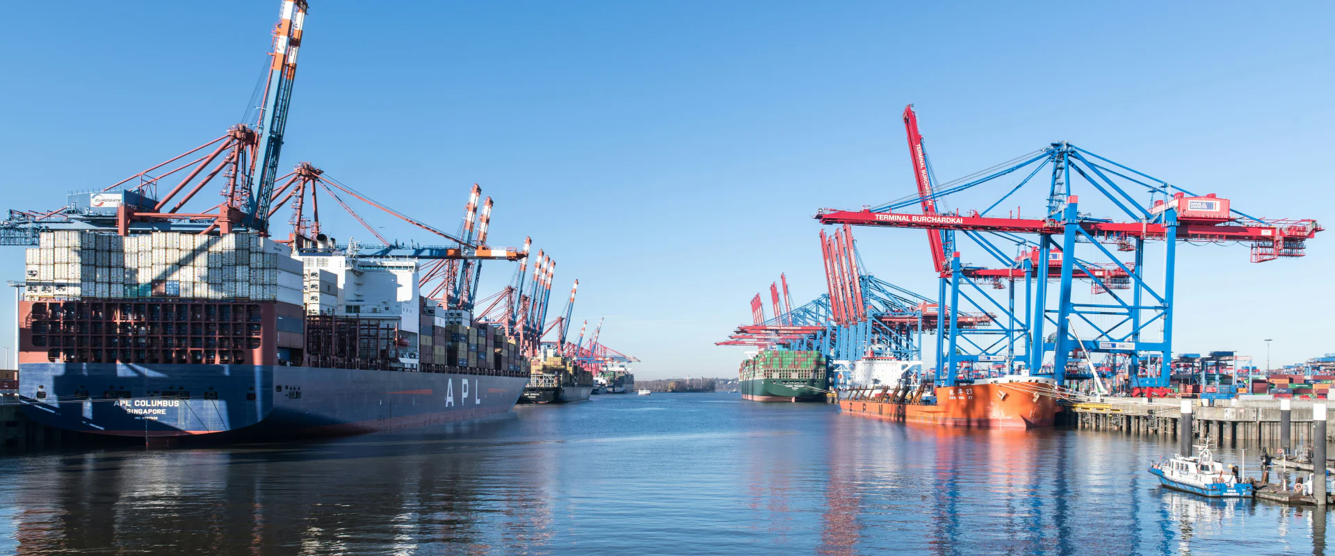 Containerhafen mit Containerbrücken und Schiffen unter blauem Himmel