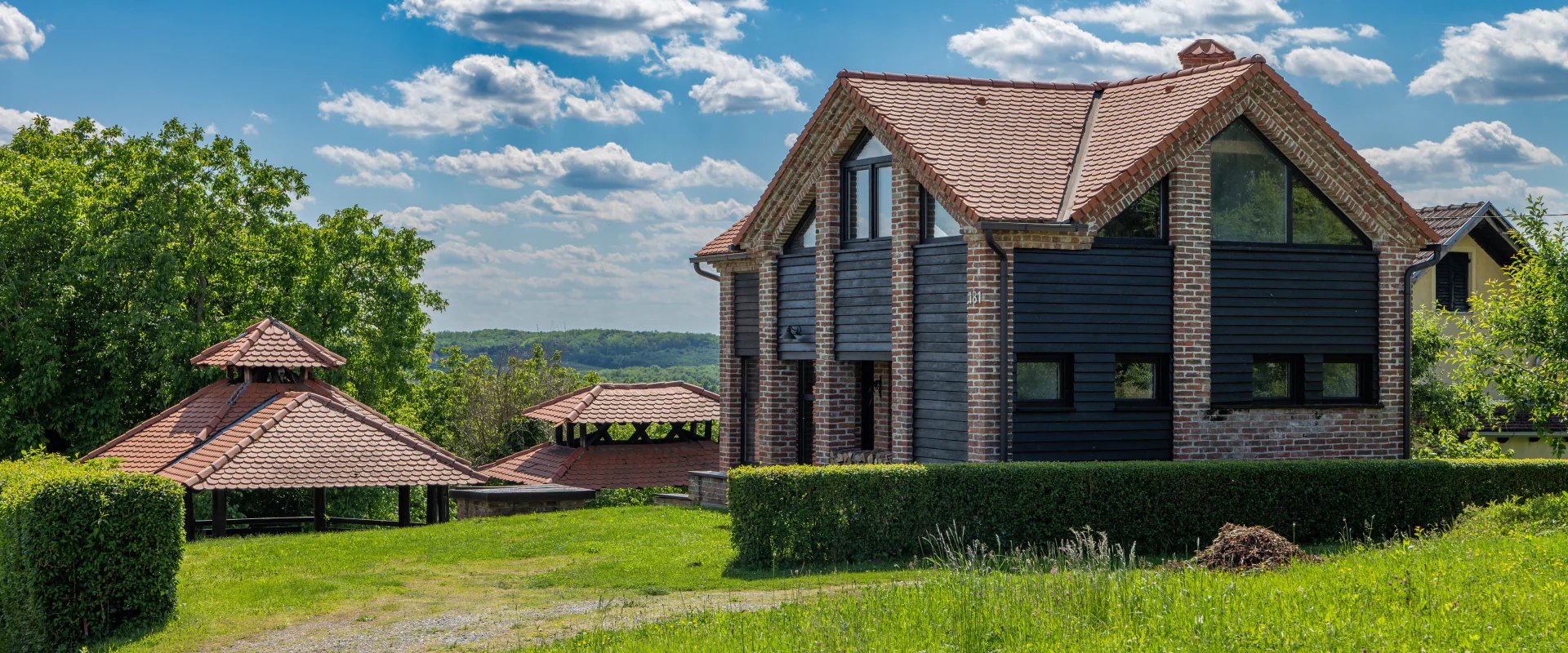 Einfamilienhaus mit Ziegeldach hinter grünem Rasen unter blauem Himmel
